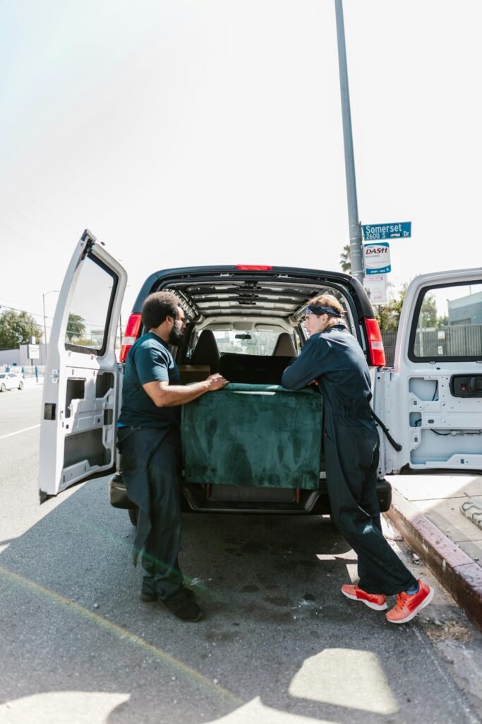 Two movers load a van with furniture during moving day.